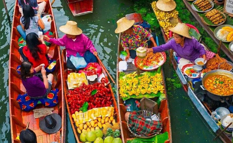 Longtail boat cruising through Damnoen Saduak floating market stalls on a Bangkok floating market and train market day trip, Thailand