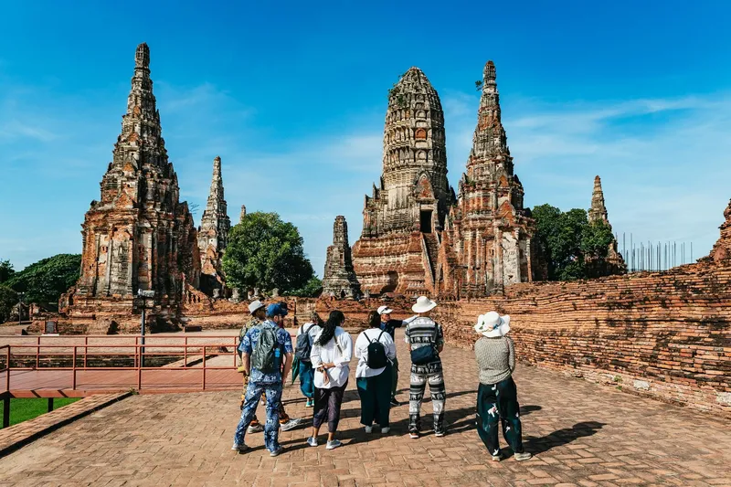 Tour group standing before the towering prang of Wat Phra Ram at Ayutthaya on a guided Bangkok Thailand tours ancient temples day trip with lunch