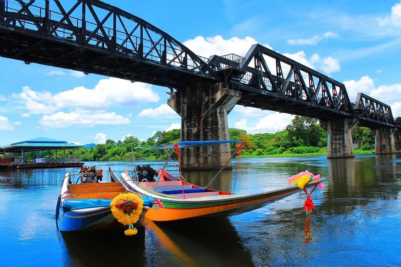 The historic Bridge on the River Kwai spanning the river in Kanchanaburi on a Bangkok Thailand tours historical day trip to the River Kwai