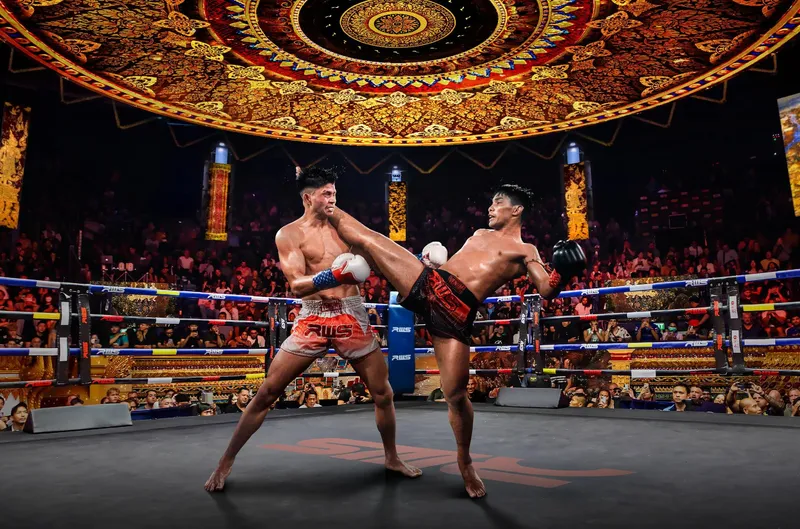 Two Muay Thai fighters in a lit ring at Rajadamnern Stadium Bangkok with crowd watching on a Bangkok Thailand tours Muay Thai evening experience