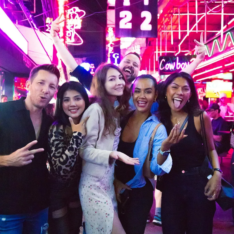 Group enjoying sunset cocktails on a Bangkok rooftop bar with the city skyline glowing at dusk on a Bangkok Thailand tours nightlife bar crawl evening