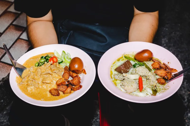 Small group of guests gathered around a Bangkok street food stall with a chef guide on an exclusive Bangkok Thailand tours food experience