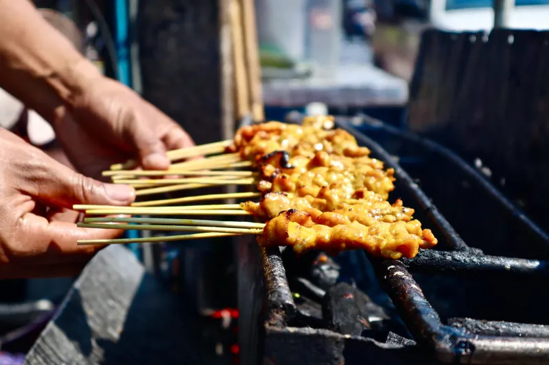 Steaming woks and neon signs lining Yaowarat Road at night on a Chinatown street food Bangkok Thailand tours evening experience