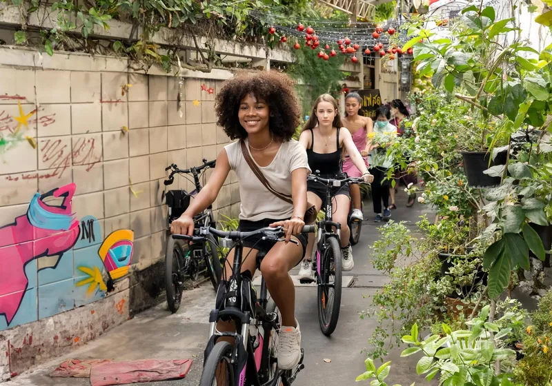 Small cycling group pausing at a canal-side street food stall in Bangkok backstreets on a Bangkok Thailand tours hidden bike food experience